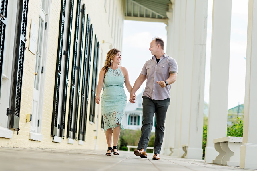A couple holding hands and walking in the town of Cape May for their engagement session.